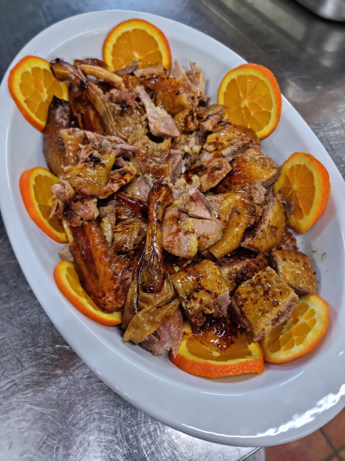 Carne arrosto su un piatto da portata con fette di arancia