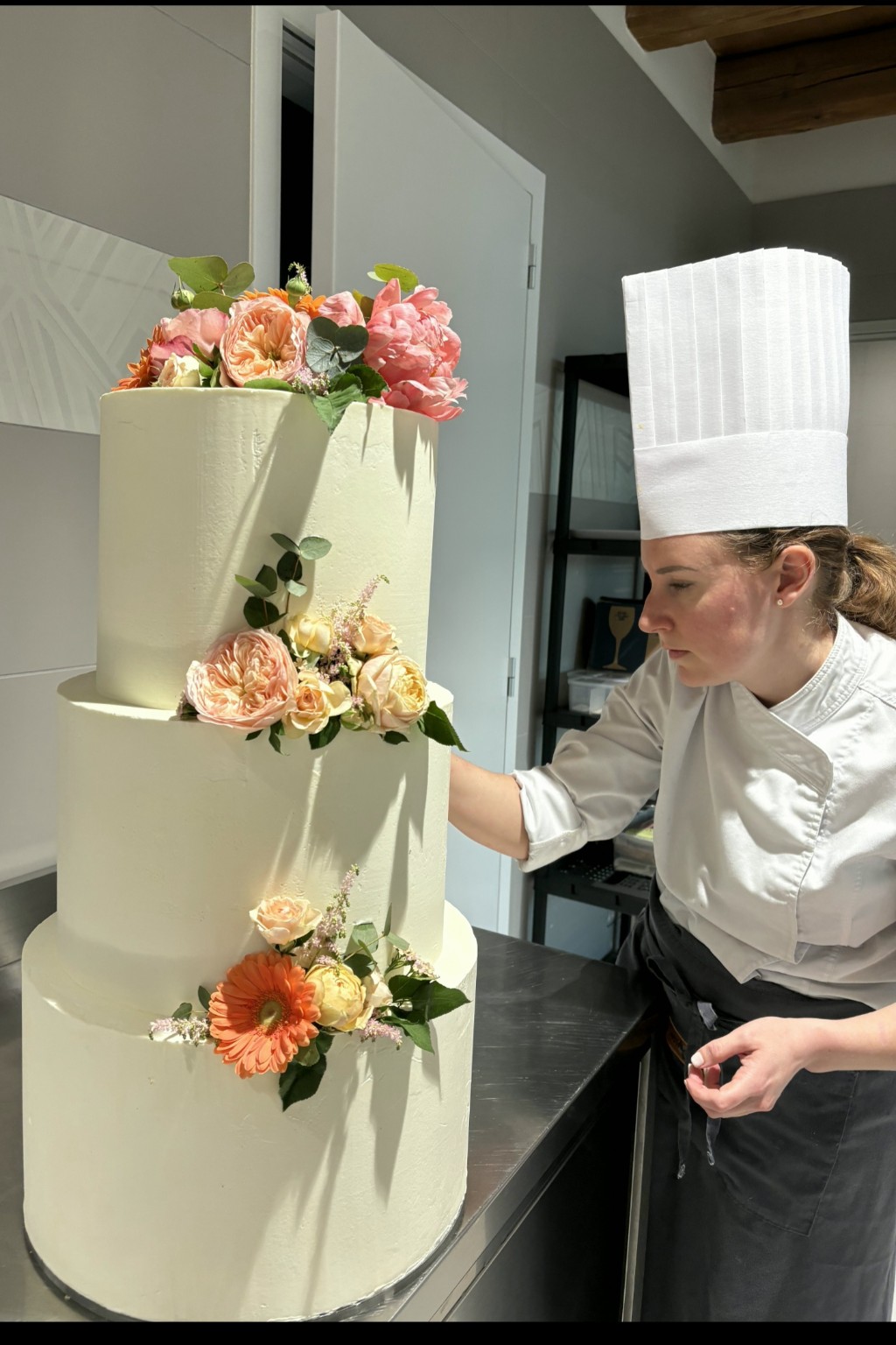 Elisa Fornasiero al lavoro su una torta a piani con decorazioni floreali